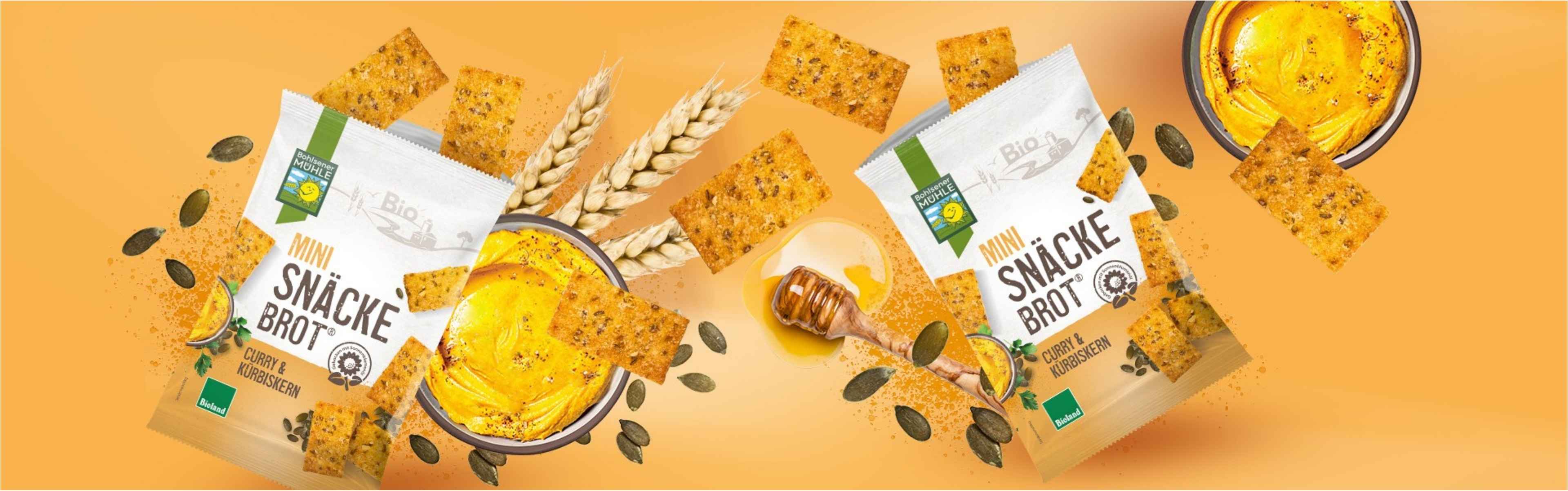 Bohlsener Mühle Mini Snäcke Brot mit Curry und Kürbiskernen, umgeben von Kürbiskernen und Dip.