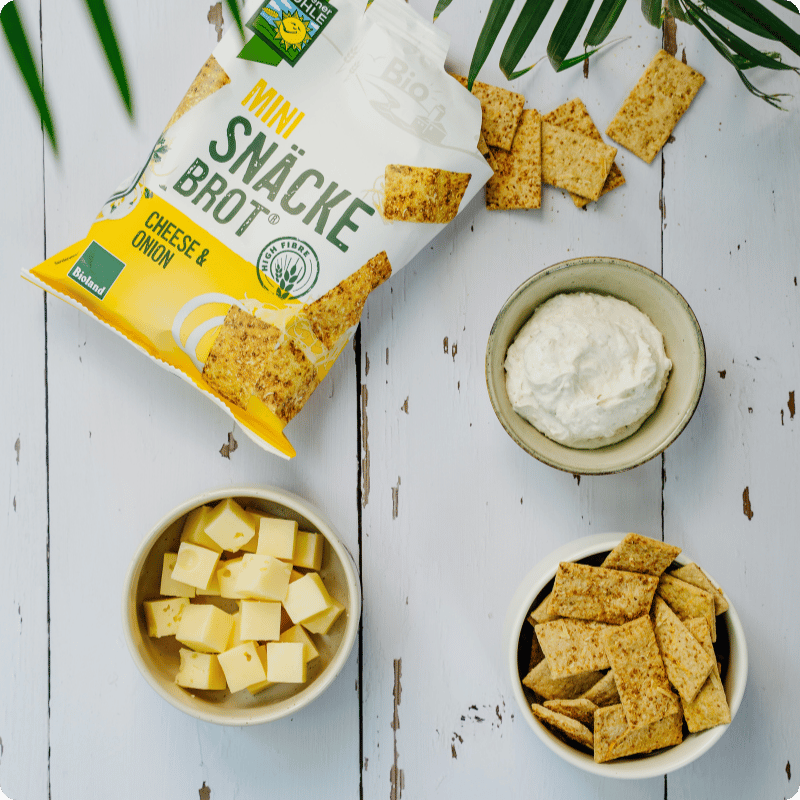 Bohlsener Mühle Mini Snäcke Brot mit Käse und Zwiebeln, serviert mit Quark und Käsewürfeln.