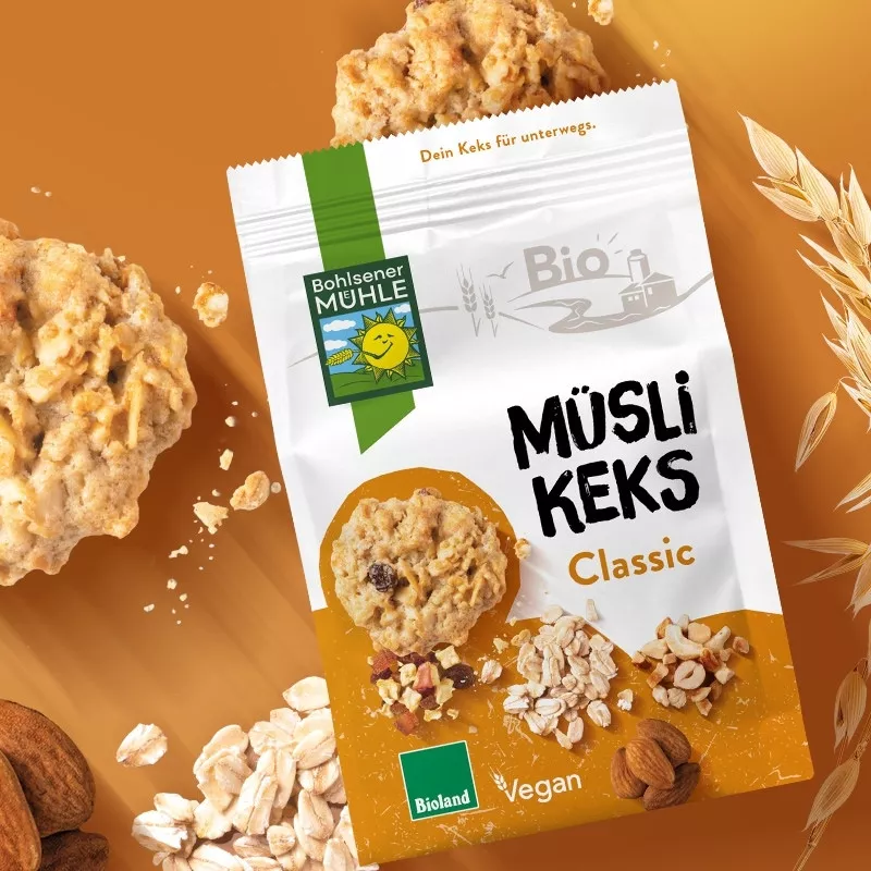 Bohlsener Mühle Müsli Keks Classic mit Nüssen und Haferflocken auf orangefarbenem Hintergrund.