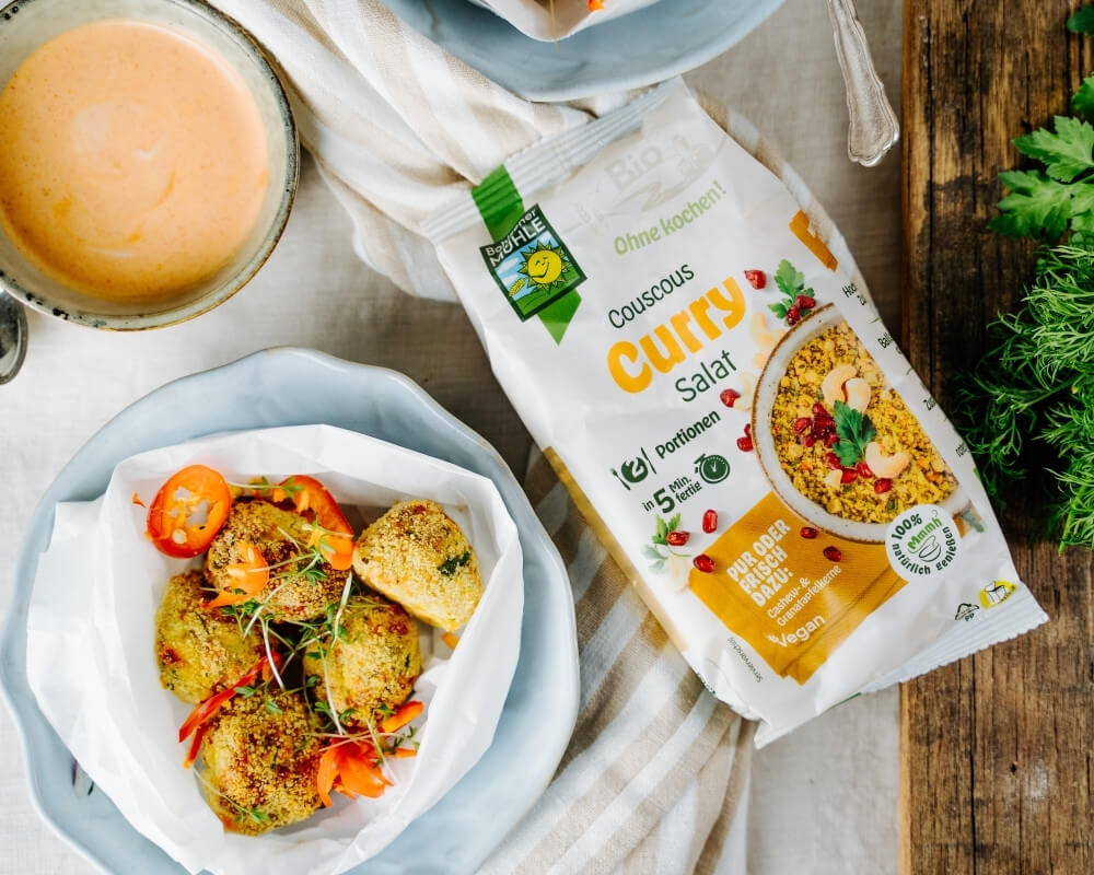 Bohlsener Mühle Bio-Couscous-Curry-Salat mit Falafel, Sauce und frischen Kräutern zur Förderung einer nachhaltigen Landwirtschaft.