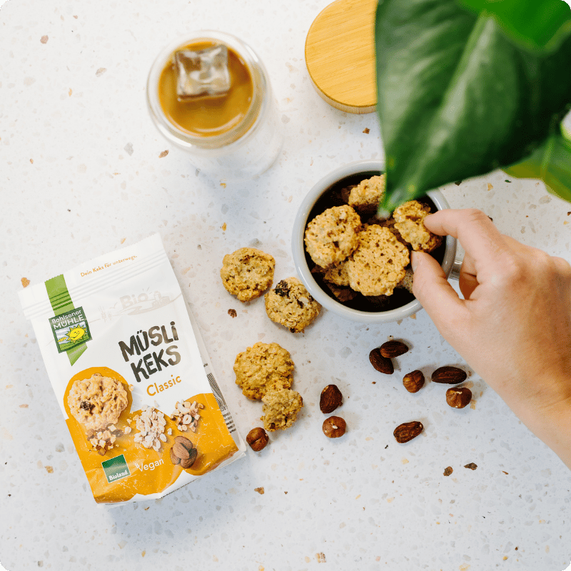 Bohlsener Mühle Müsli Keks Classic in einer Schüssel mit Nüssen und einem Getränk.