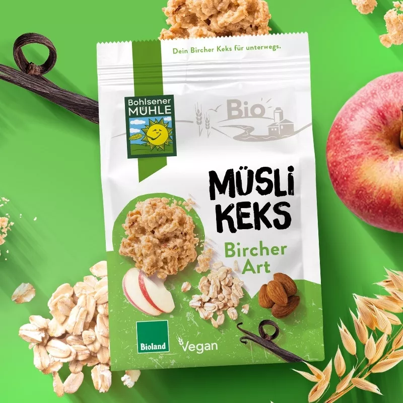Bohlsener Mühle Müsli Keks Bircher Art mit Äpfeln, Mandeln und Haferflocken auf grünem Hintergrund.