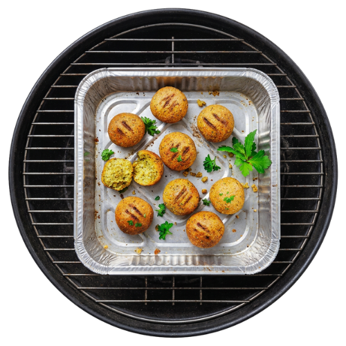 Bohlsener Mühle Falafel Bällchen liegen in einer Grillschale auf einem schwarzen Grillrost mit grüner Petersilie.