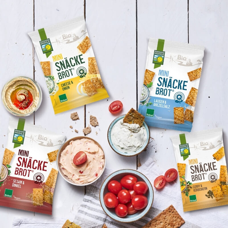 Bohlsener Mühle Mini Snackbrot Sorten mit Dips und Tomaten auf einem Tisch.