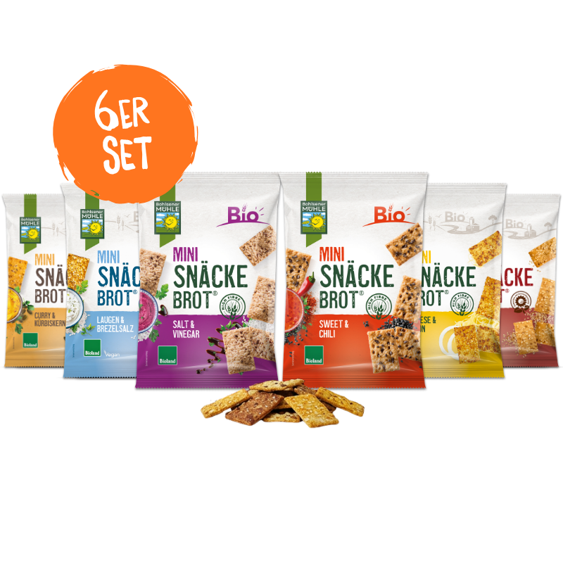Sechs Packungen Bohlsener Mühle Mini Snäckebrot in verschiedenen Sorten mit einigen losen Crunchy Stücken davor.