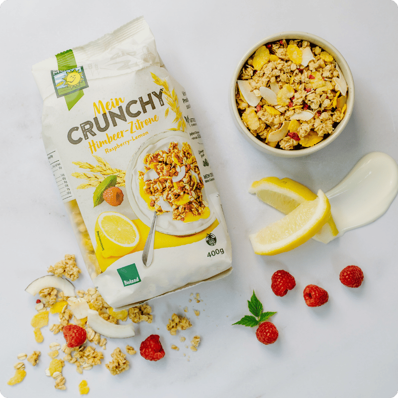 Bohlsener Mühle Mein Crunchy Himbeer-Zitrone in einer Schüssel mit frischen Himbeeren und Zitronenscheiben.