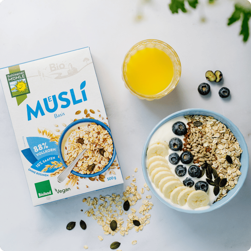 Bohlsener Mühle Bio Müslí mit Haferflocken, Bananen und Heidelbeeren in einer Schüssel.