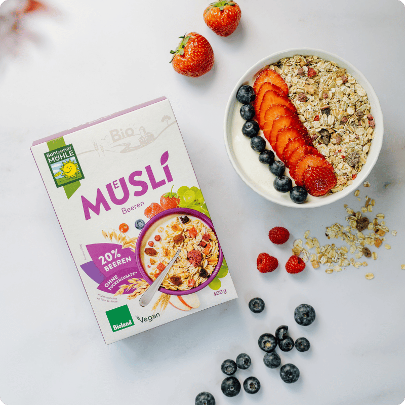 Bohlsener Mühle Müsli Beeren mit frischen Erdbeeren und Heidelbeeren in einer Schüssel.