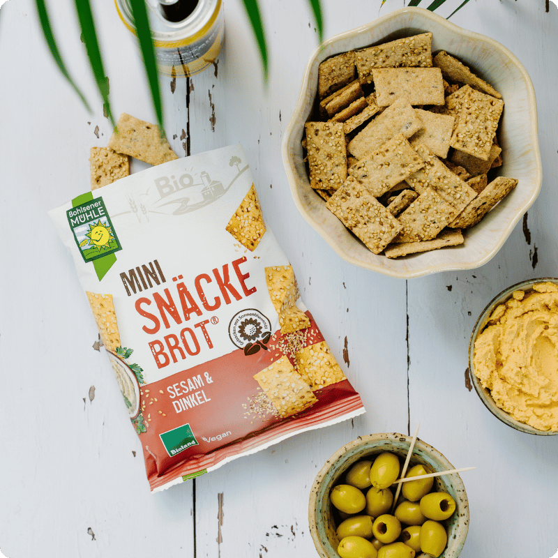 Bohlsener Mühle Mini Snäcke Brot mit Sesam und Dinkel, serviert mit Oliven und Hummus.