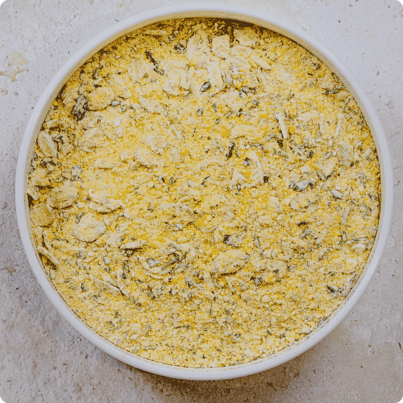 Blick von oben in eine Dose mit gelber Bohlsener Mühle Crunchy Mischung aus Getreideflocken und Kräutern.