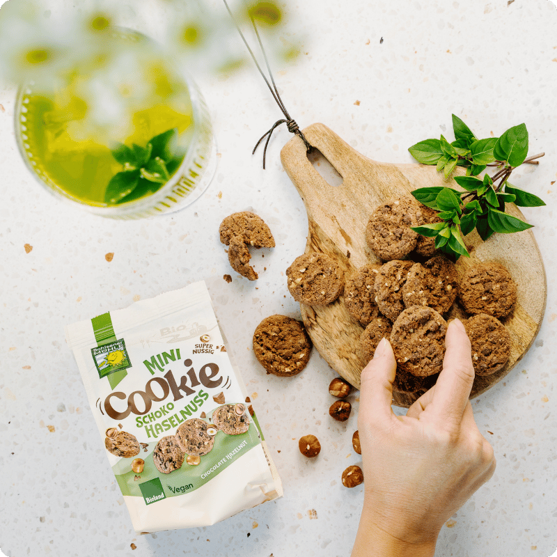 Bohlsener Mühle Mini Cookie Schoko Haselnuss auf einem Holzbrett mit frischen Kräutern.