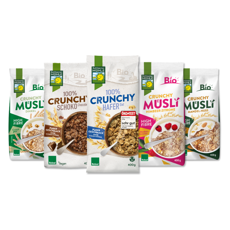 Fünf verschiedene Packungen Bohlsener Mühle Crunchy Müsli in einer Reihe auf schwarzem Hintergrund präsentiert.