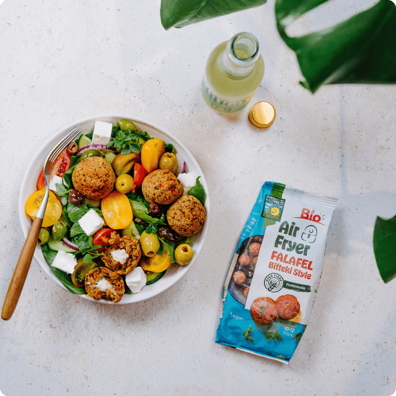 Bohlsener Mühle Air Fryer Falafel Bifteki Style neben einer Schüssel mit frischem Salat und Feta-Käse.