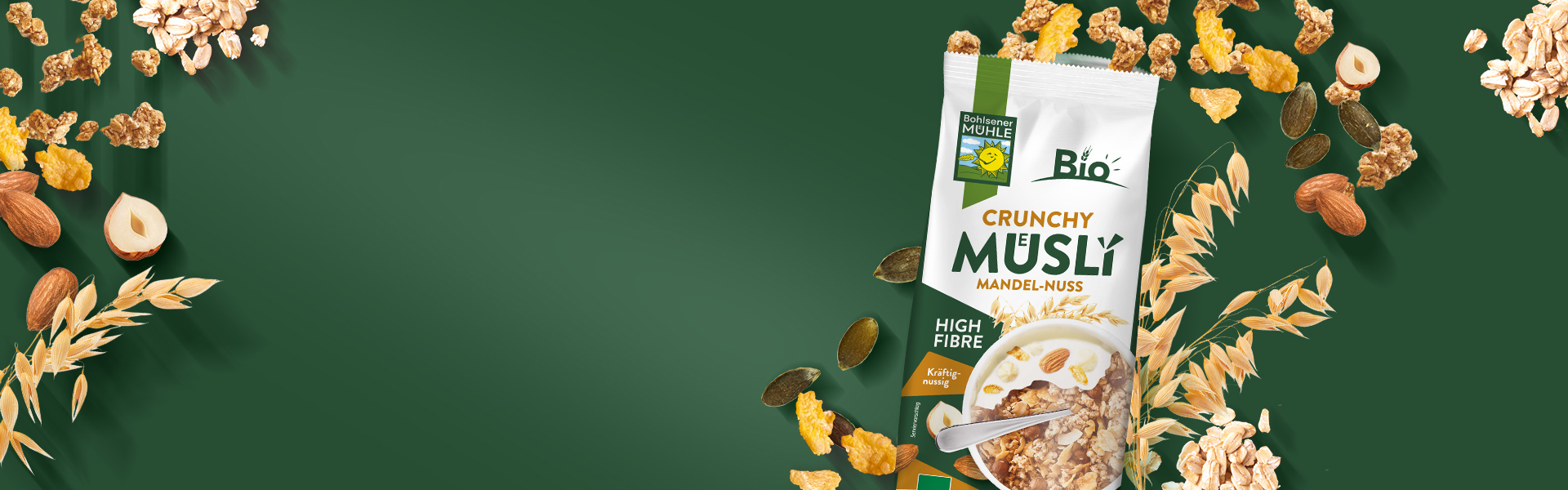 Bohlsener Mühle Crunchy Müsli Mandel-Nuss umgeben von Haferflocken, Nüssen und Kürbiskernen auf grünem Hintergrund.
