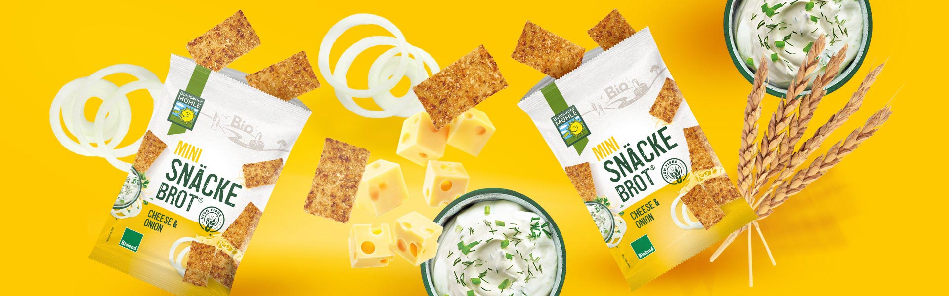 Bohlsener Mühle Mini Snäcke Brot Cheese & Onion mit Käsewürfeln, Zwiebelringen und Kräuterquark auf gelbem Grund.