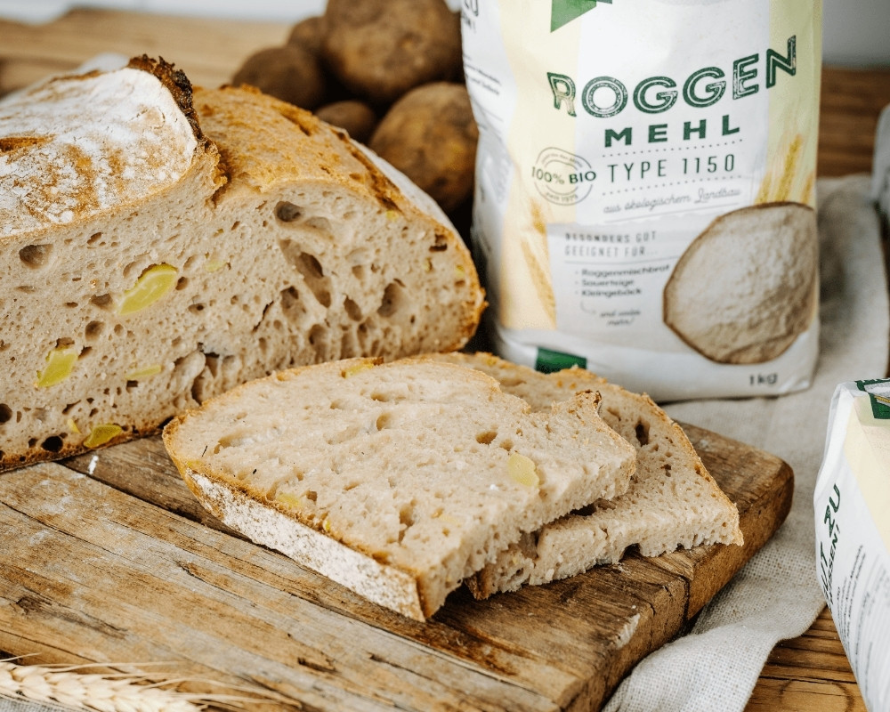 Bohlsener Mühle Roggenbrot mit sichtbaren Kartoffelstücken auf Holzbrett.
