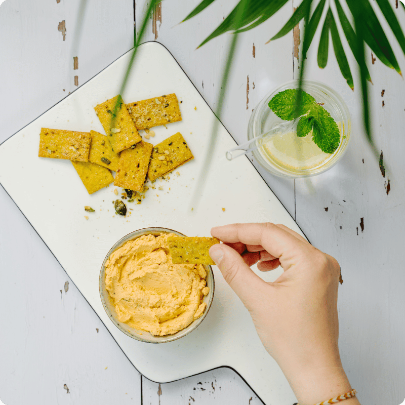Bohlsener Mühle Crunchy Cookies mit Hummus und Getränk auf einem Tisch.