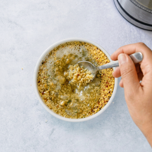 Eine Hand rührt in einer Schüssel mit Bohlsener Mühle Crunchy Cookie Mischung und Wasser.