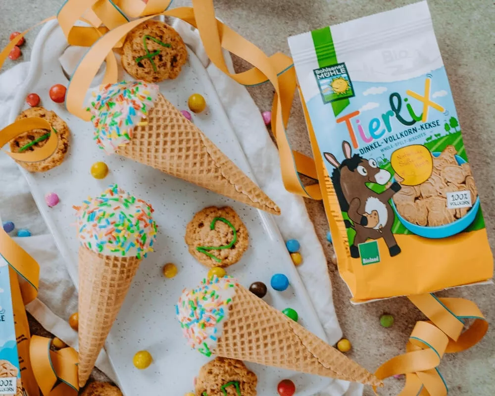 Bohlsener Mühle Bio-Dinkel-Vollkorn-Tiercracker, Eiswaffeln mit Streuseln und Kekse auf einem weißen Tuch.