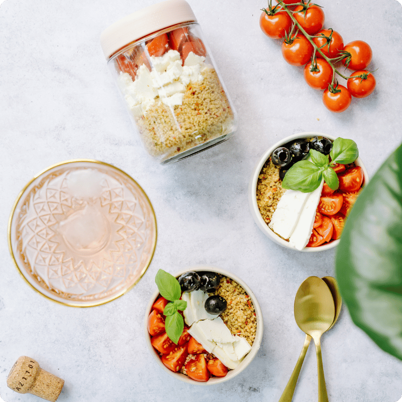 Zwei Schalen mit Couscous, Tomaten, Oliven und Basilikum von Bohlsener Mühle.