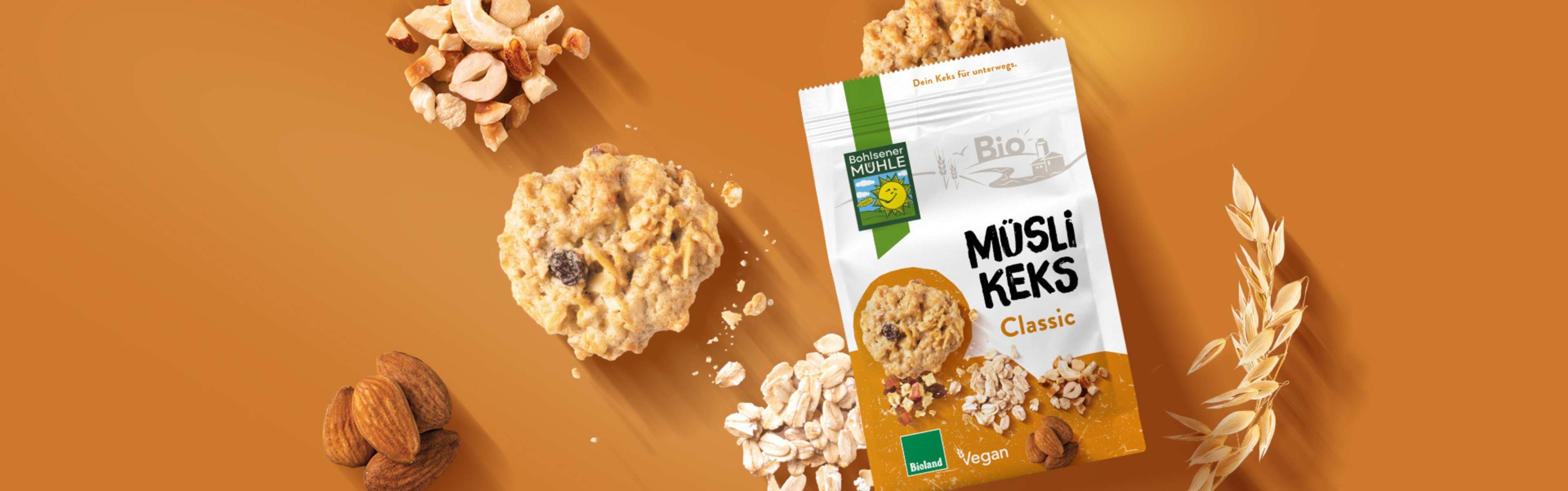Bohlsener Mühle Müsli Keks Classic mit Nüssen und Haferflocken auf orangefarbenem Hintergrund.