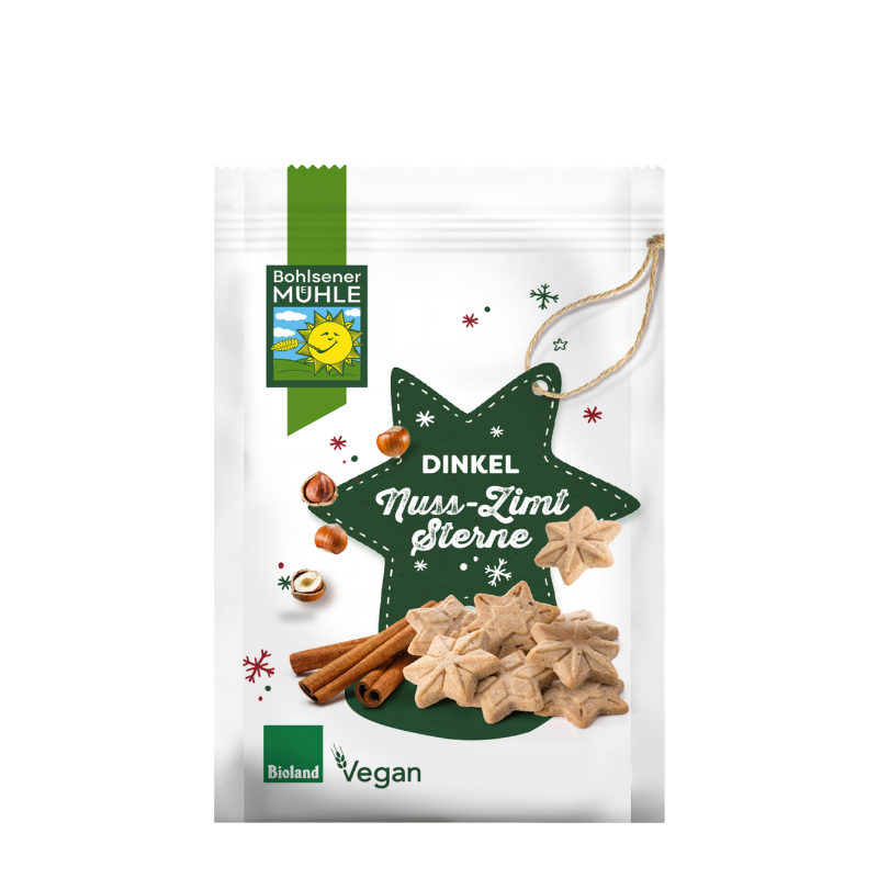 Bohlsener Mühle Dinkel Nuss-Zimt Sterne Cookie Packung mit Zimtstangen und Haselnüssen auf weißem Hintergrund.