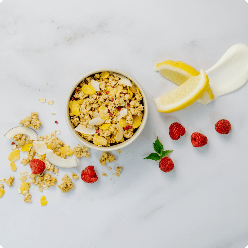 Bohlsener Mühle Müsli mit Kokos, Himbeeren und Zitronenscheiben in einer Schüssel.
