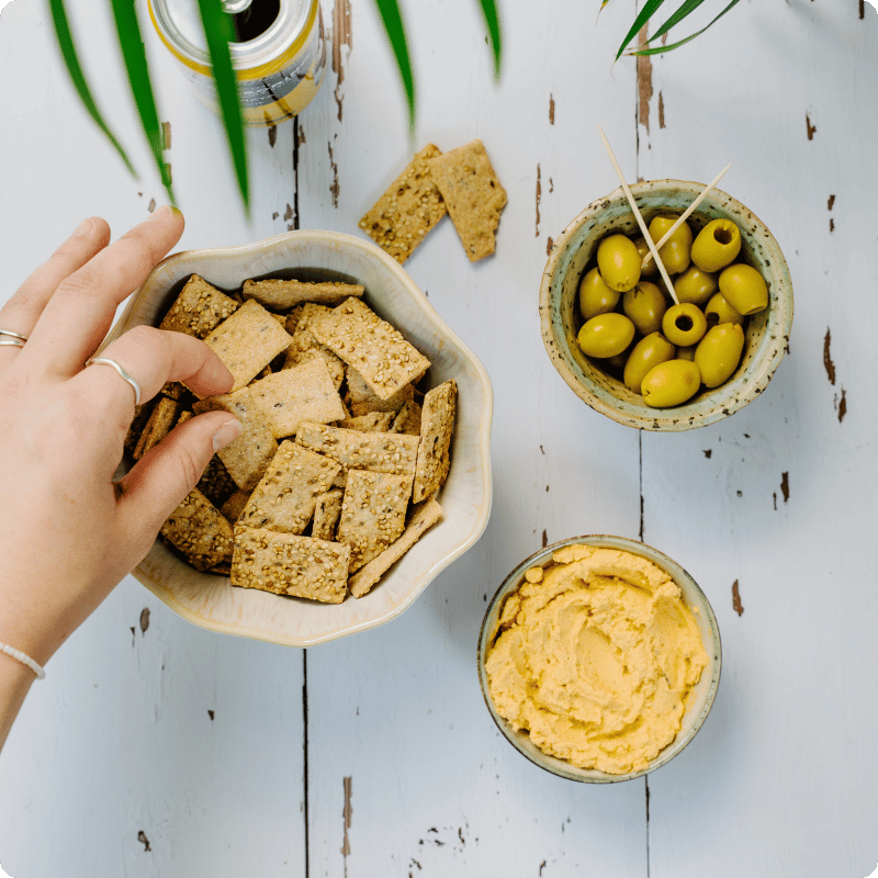 Bohlsener Mühle Knusprige Kekse in einer Schüssel mit Oliven und Hummus.