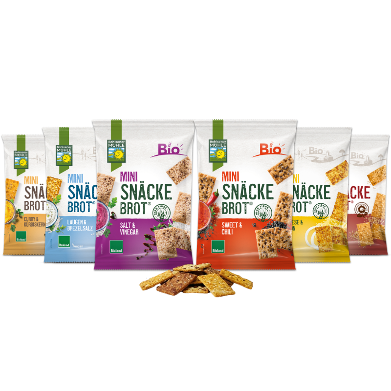Sechs verschiedene Packungen Bohlsener Mühle Mini Snäcke Brot mit losem Crunchy Knäckebrot davor auf schwarzem Grund.