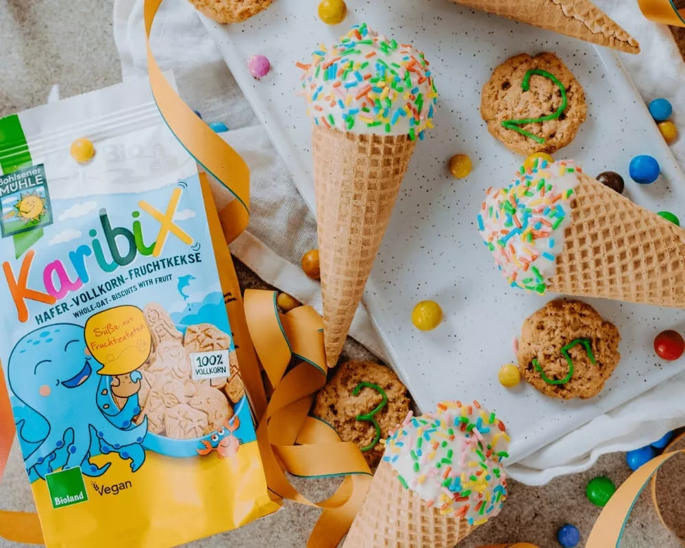 Bohlsener Mühle Karibix Vollkorn-Haferkekse mit Früchten, Eistüten mit Streuseln und Kekse auf einem weißen Tablett.