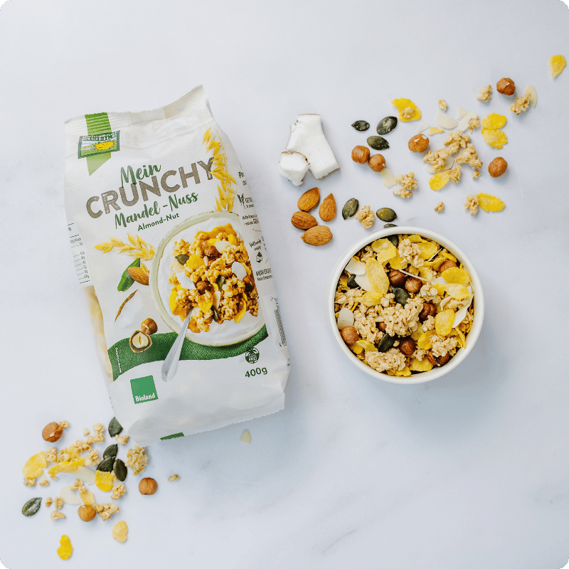 Bohlsener Mühle Mein Crunchy Mandel-Nuss in einer Schüssel mit Nüssen und Flocken.