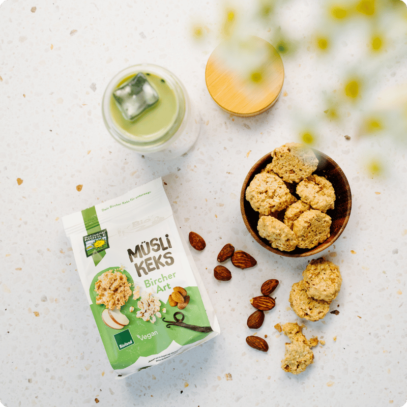 Bohlsener Mühle Müsli Keks Bircher Art in einer Schüssel mit Mandeln und einem Getränk.