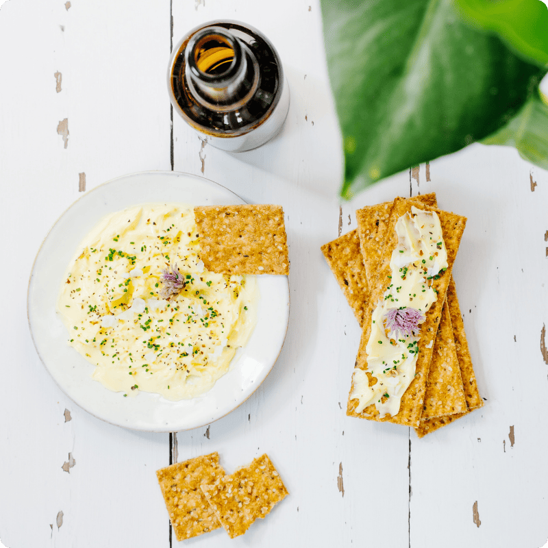 Bohlsener Mühle Crunchy Cracker mit Kräuterquark auf einem weißen Holztisch serviert.
