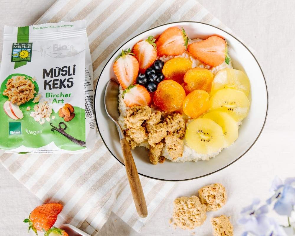 Bohlsener Mühle Müsli Keks Bircher Art auf einem Teller mit frischem Obst und Joghurt.