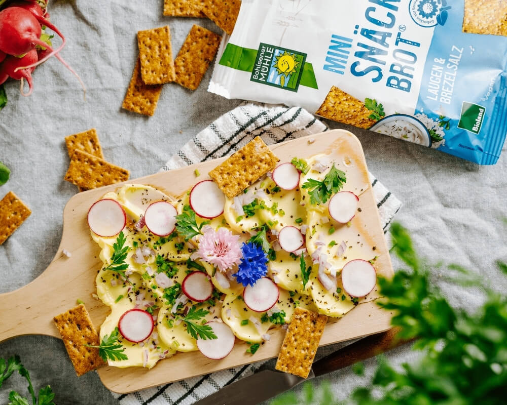 Bohlsener Mühle Bio-Snäckebrot mit Rettich, Schnittlauch und essbaren Blüten.