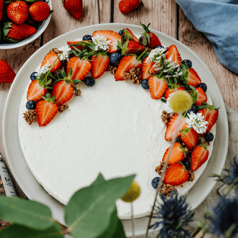 Bohlsener Mühle Torte mit Erdbeeren, Blaubeeren und Crunchy Cookie auf einem Teller.
