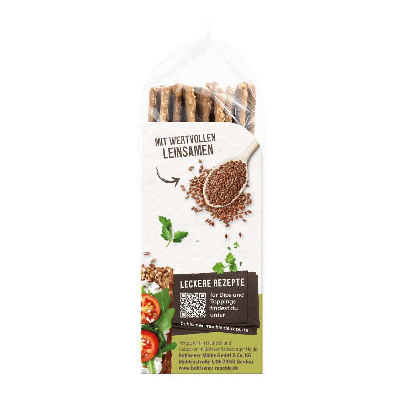 Bohlsener Mühle Leinsamen Knäckebrot in der Packung mit einem Holzlöffel voller Leinsamen und Tomaten-Topping.
