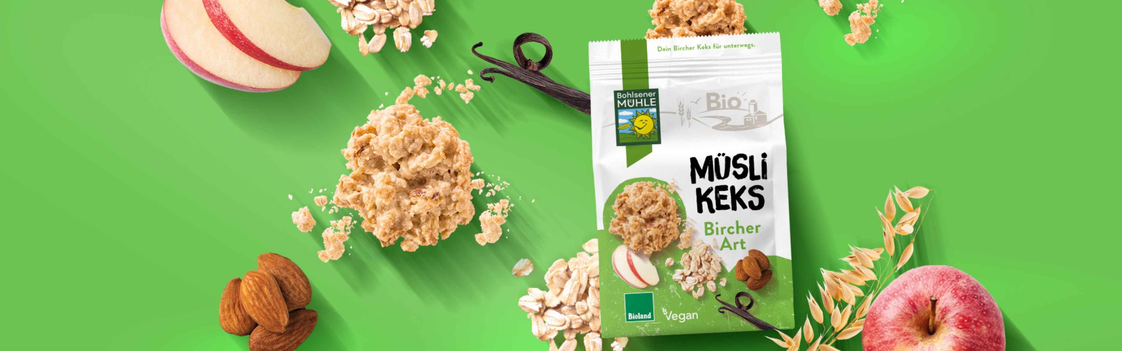 Bohlsener Mühle Müsli Keks Bircher Art mit Äpfeln, Mandeln und Haferflocken auf grünem Hintergrund.