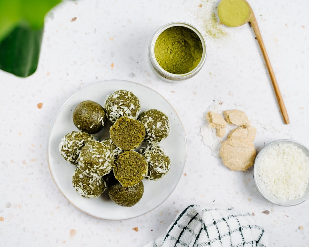 Bohlsener Mühle Crunchy Cookie Bällchen mit Kokosraspeln und Matcha-Pulver auf einem Teller.