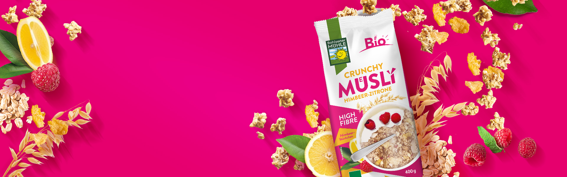 Bohlsener Mühle Crunchy Müsli Himbeer-Zitrone umgeben von frischen Himbeeren, Zitronenscheiben und Haferflocken.