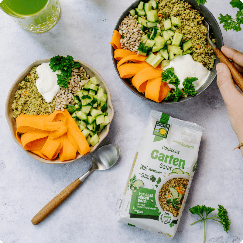 Zwei Schalen mit Bohlsener Mühle Couscous Garten Salat, Gemüse und Joghurt.