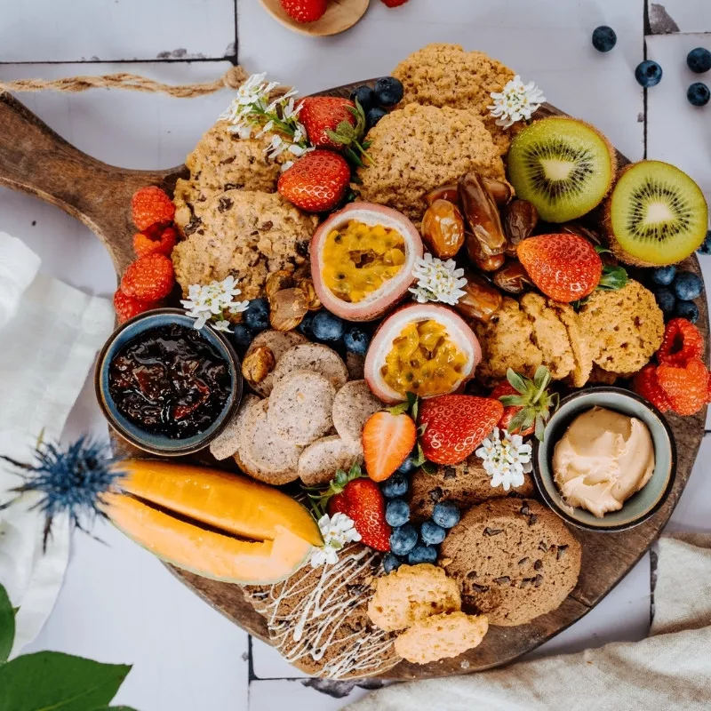 Bohlsener Mühle Crunchy Cookies mit frischen Früchten und Dips auf einem Holzbrett.