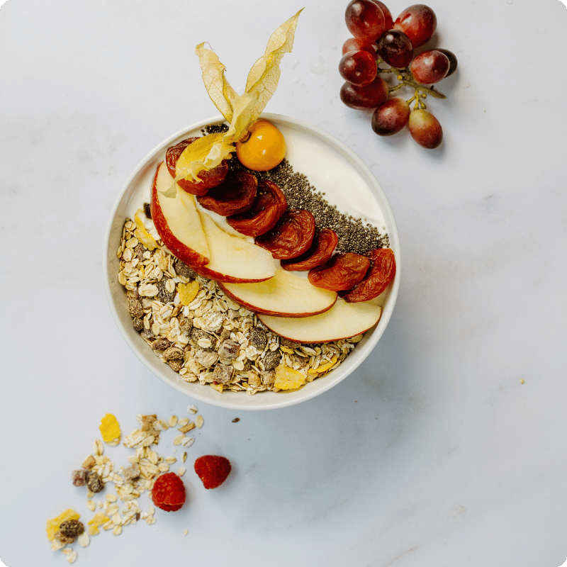 Bohlsener Mühle Müsli mit Äpfeln, Chiasamen und Trauben in einer Schüssel.