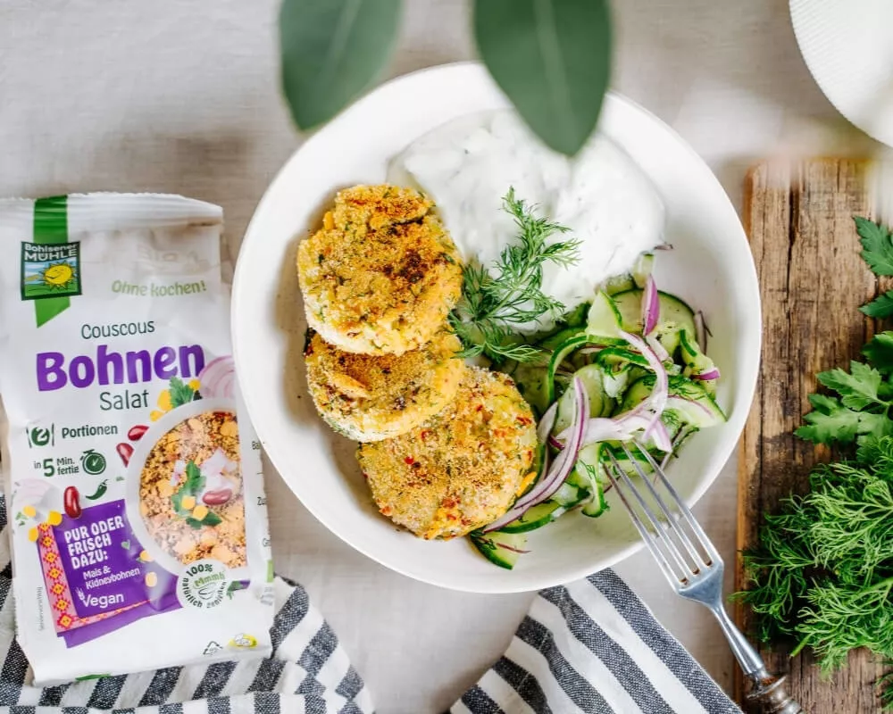 Bohlsener Mühle Bio-Couscous-Bohnensalat, knusprige Patties, Gurke, rote Zwiebeln, Dill und Joghurtsauce.