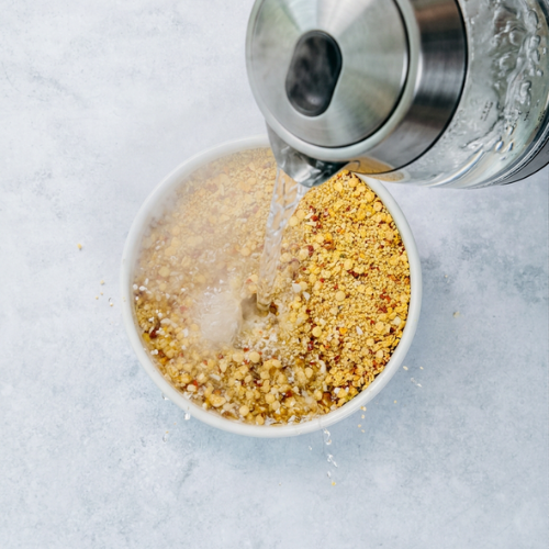 Heißes Wasser wird in eine Schüssel mit Bohlsener Mühle Crunchy gegossen.