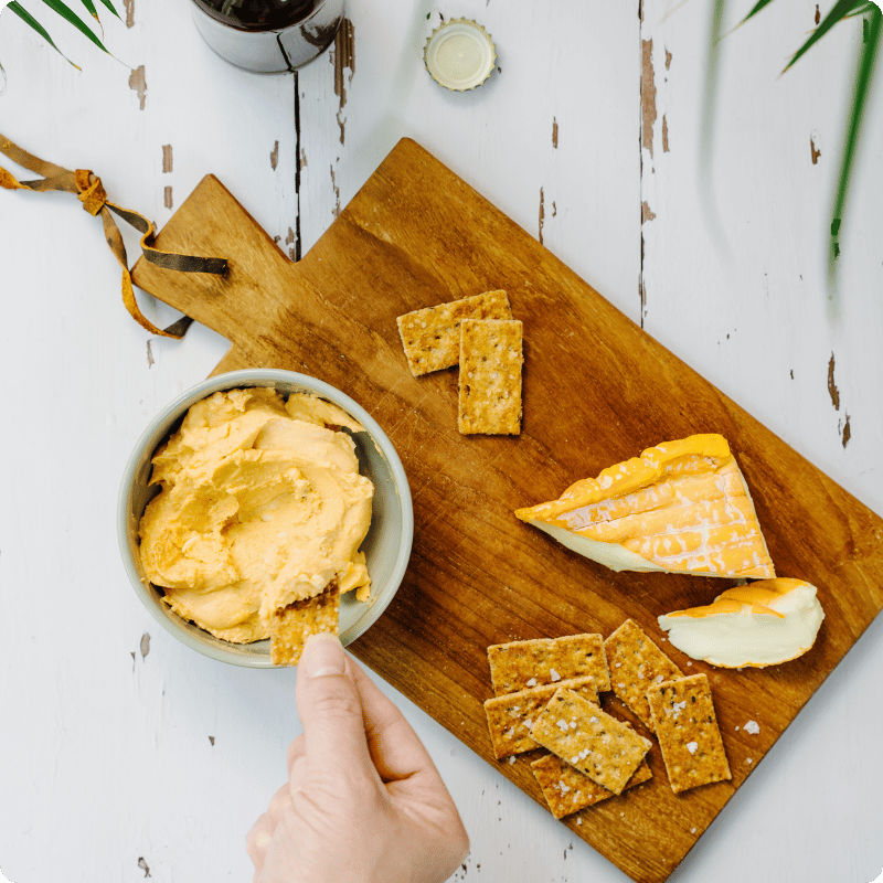 Bohlsener Mühle Crunchy Cookie mit Käse und Dipp auf Holzbrett.