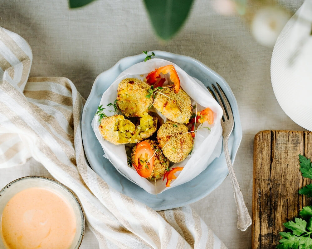 Knusprig gebackene Bio-Gemüsebratlinge von der Bohlsener Mühle, serviert mit frischen Tomaten und einem cremigen Dip.
