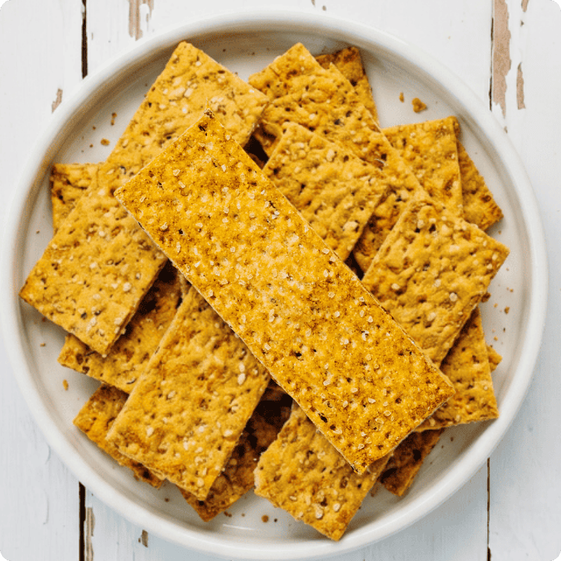 Ein Teller mit Bohlsener Mühle Crunchy Hafer-Keksen auf einem weißen Holztisch.