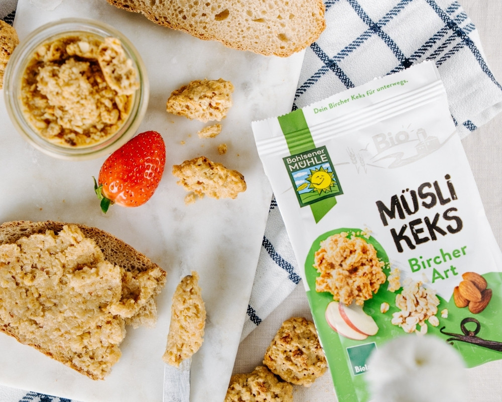 Bohlsener Mühle Müsli Keks Bircher Art auf einem Tisch mit Erdbeere und Brot.